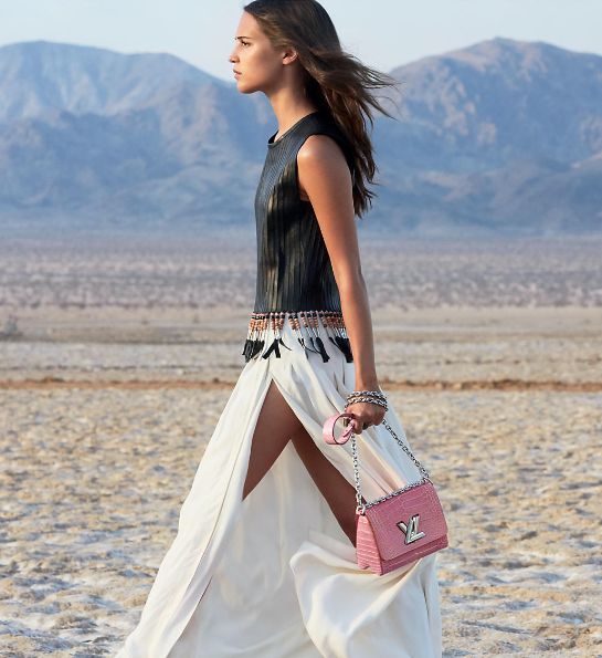 Woman walking in a desert with a pink handbag